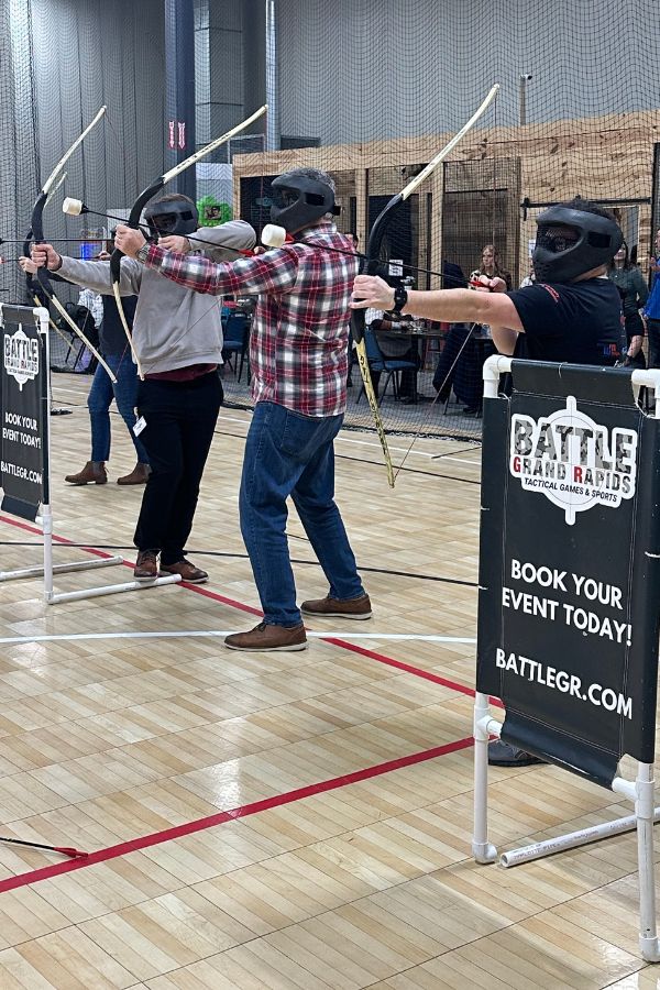 Adult social event with 3 men playing archery tag