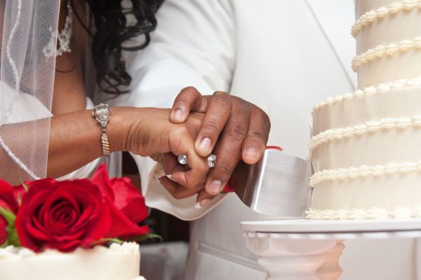 African American couple cutting wedding cake holding hands at a grand rapids wedding event venue