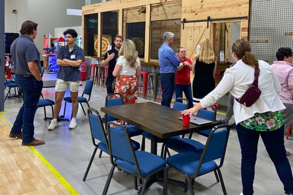 Group of professionals networking near the axe throwing lanes at BGR