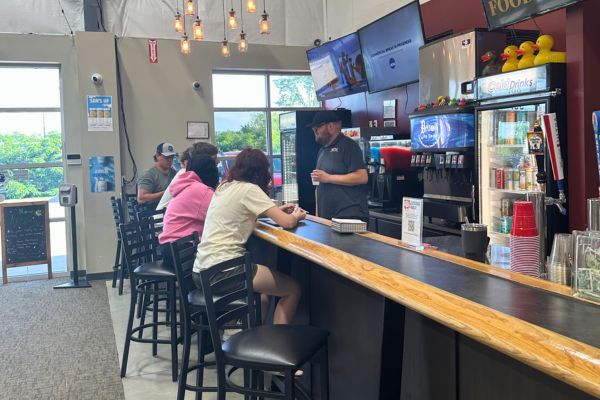 People sitting at the bar and the bartender talking